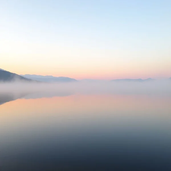 Synonyms for Serene: A peaceful, calm lake at dusk reflecting the sky